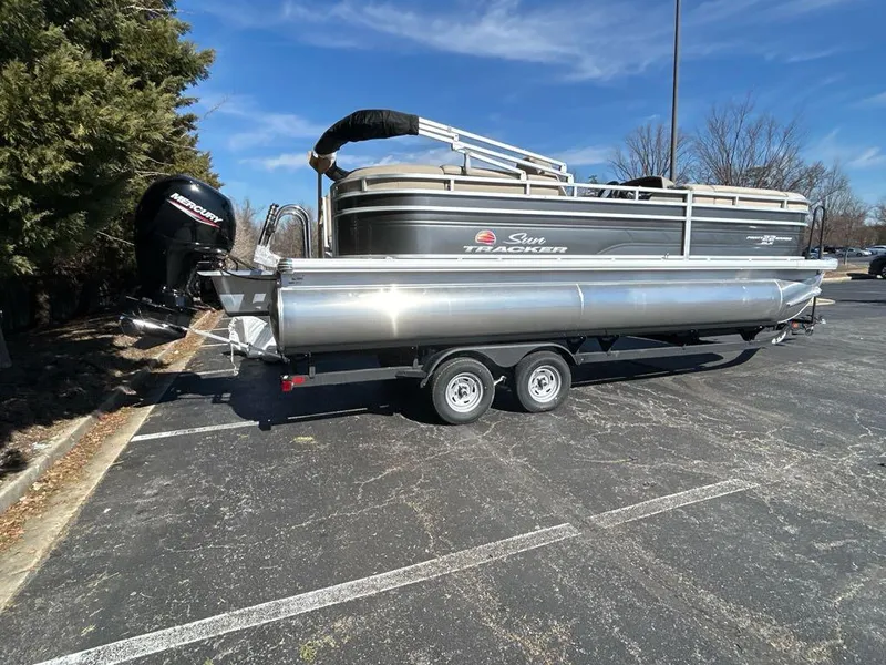 Slide: The Image of 2025 Sun Tracker Party Barge 22 DLX pontoon boat on trailer in parking lot. - 2