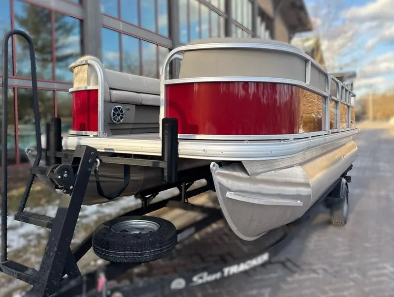 Slide: The Image of 2025 Sun Tracker Party Barge 18 DLX pontoon boat on trailer, red and silver design. - 4