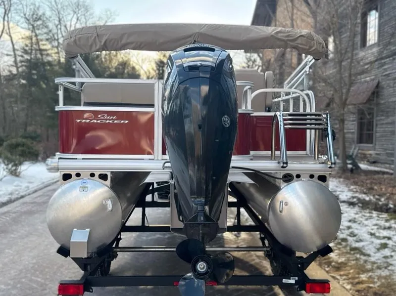 Slide: The Image of 2025 Sun Tracker Party Barge 18 DLX pontoon boat with outboard motor, parked outdoors. - 5