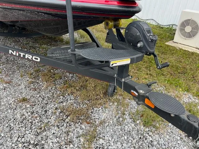 Slide: The Image of 2018 Nitro Z21 DC boat trailer on gravel, featuring winch and step platform. - 11