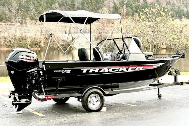 Slide: The Image of 2025 Tracker Pro Guide V-16 WT boat with canopy on a trailer by a lake. - 74