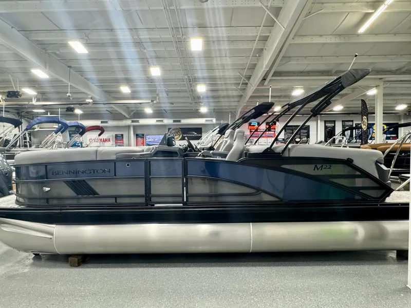 Slide: The Image of 2025 Bennington M Quad Bench 22 MFB pontoon boat displayed in a showroom. - 23