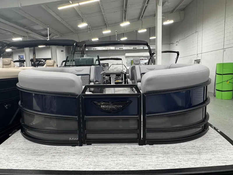 Slide: The Image of 2025 Bennington M Quad Bench 22 MFB pontoon boat in showroom, featuring sleek design and comfortable seating. - 3