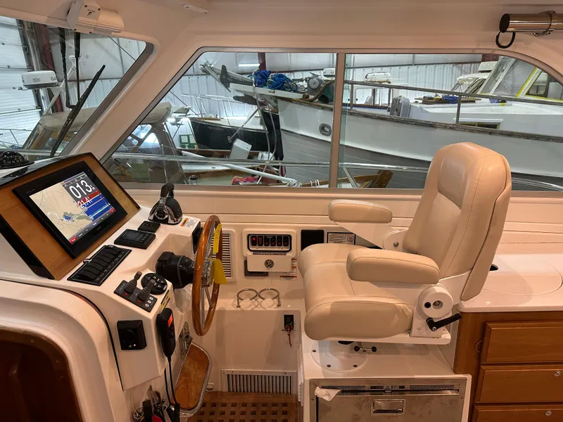 Slide: The Image of 2018 Back Cove 32 helm with navigation system and captain's chair in a boatyard setting. - 11