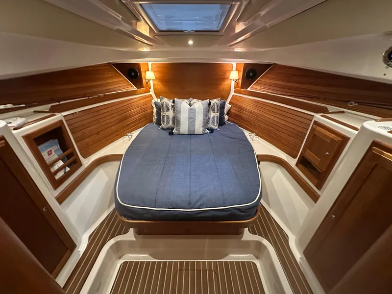 Slide: The Image of 2018 Back Cove 32 cabin interior with cozy bed, wooden paneling, and ambient lighting. - 14