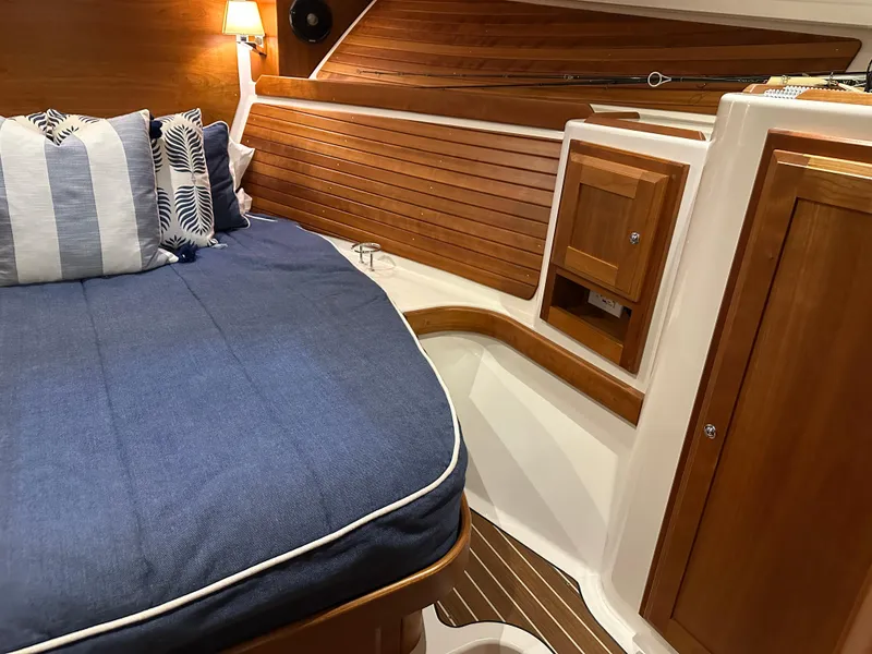 Slide: The Image of 2018 Back Cove 32 interior with blue bedding, wooden paneling, and built-in storage. - 17