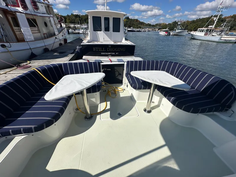 Slide: The Image of 2018 Back Cove 32 boat with striped seating and tables, docked in a scenic marina. - 29