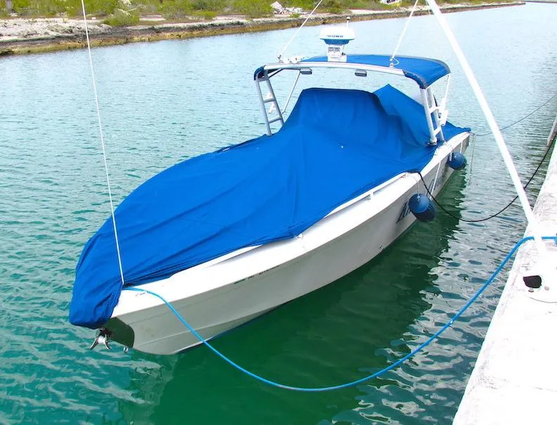 Slide: The Image of 2005 Marlago F35 boat with blue cover docked in calm water. - 14