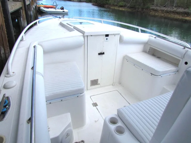 Slide: The Image of 2005 Marlago F35 boat interior with white seating and storage, docked by calm water. - 15