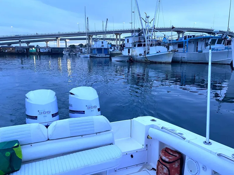 Slide: The Image of 2005 Marlago F35 boat with twin engines docked near a bridge and fishing boats. - 17