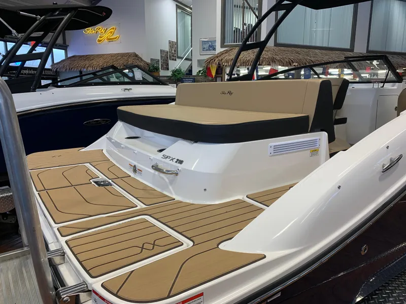 Slide: The Image of 2025 Sea Ray SPX 210 boat with tan deck and seating in showroom. - 2