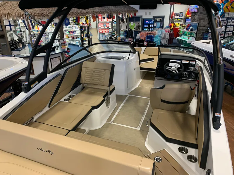 Slide: The Image of 2025 Sea Ray SPX 210 boat interior with tan seating and modern dashboard in showroom. - 5