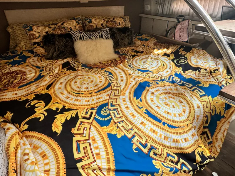 Slide: The Image of Luxurious bedding with intricate gold and blue patterns inside a 2016 Regal 32 Express boat. - 20