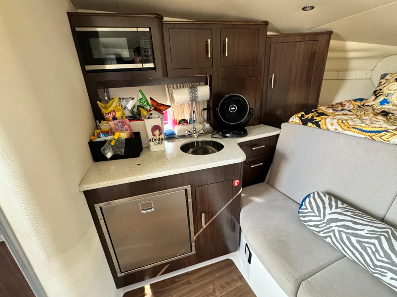Slide: The Image of 2016 Regal 32 Express cabin interior with kitchenette, snacks, microwave, and cozy seating area. - 22