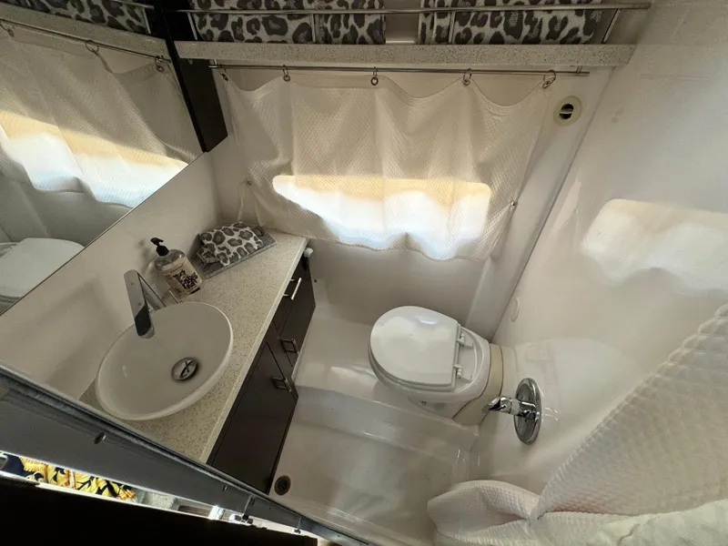 Slide: The Image of Bathroom interior of 2016 Regal 32 Express boat with sink, toilet, and curtains. - 25