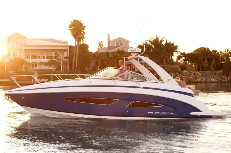 Slide: The Image of 2016 Regal 32 Express boat cruising on water at sunset near waterfront homes. - 33