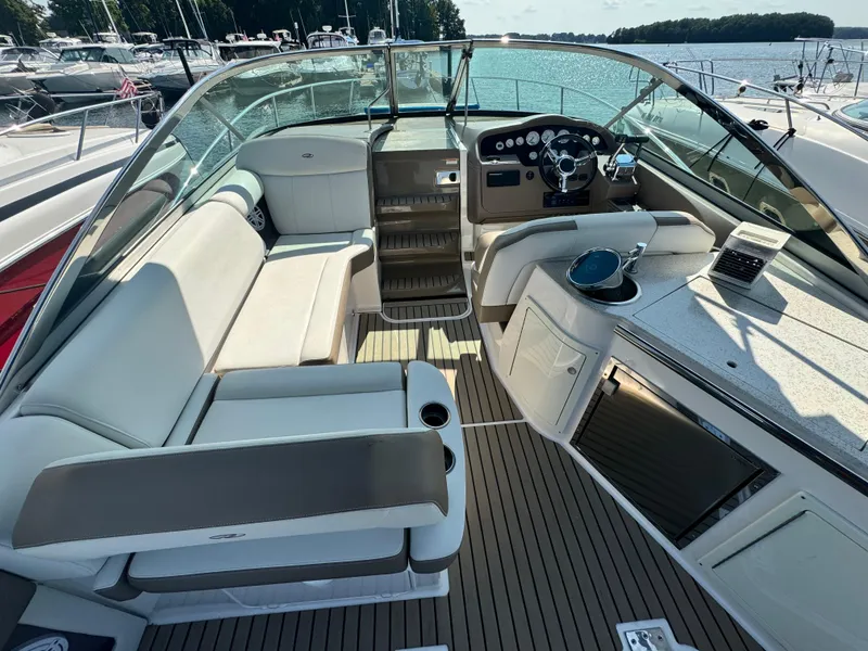 Slide: The Image of 2016 Regal 32 Express boat interior with seating, steering wheel, and dashboard, docked by the water. - 7