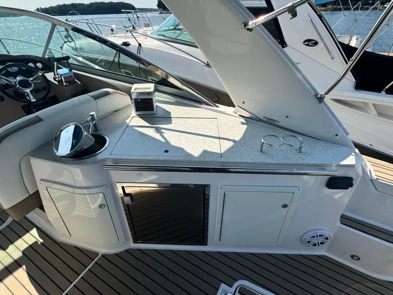 Slide: The Image of 2016 Regal 32 Express yacht interior with kitchenette and steering wheel, docked by the water. - 8