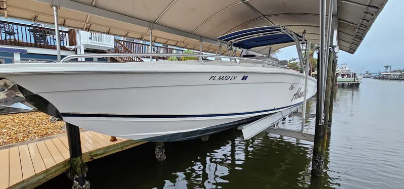 Slide: The Image of 2003 Jefferson Marlago FS35 boat docked under a canopy on a calm waterfront. - 2