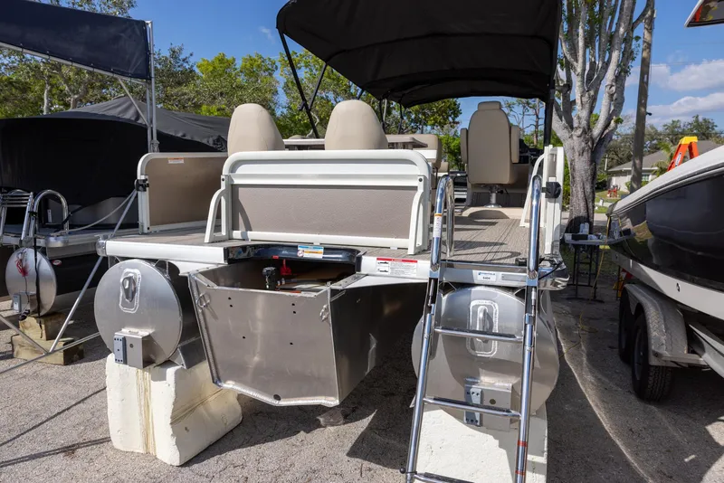 Slide: The Image of 2025 Premier 250 Sunsation RS pontoon boat with seating and canopy, parked outdoors. - 2