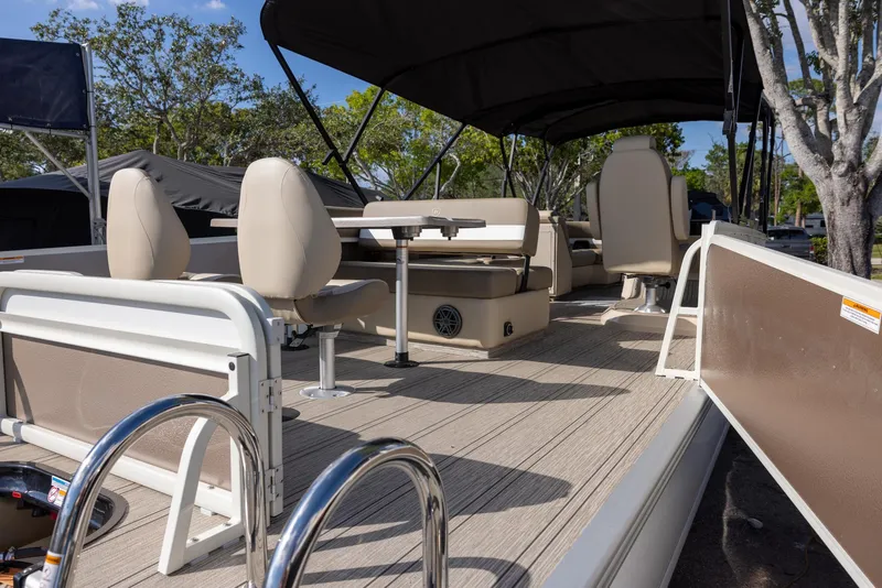 Slide: The Image of 2025 Premier 250 Sunsation RS pontoon boat with beige seating and canopy, docked outdoors. - 4