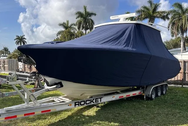 Slide: The Image of 2019 Pursuit S 328 Sport boat covered on trailer, surrounded by palm trees. - 14