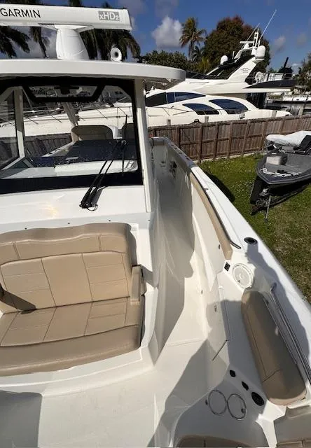 Slide: The Image of 2019 Pursuit S 328 Sport boat with beige seating, docked near other yachts. - 6
