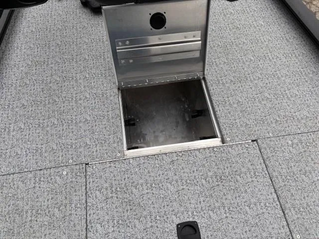 Slide: The Image of 2024 Tracker Pro 170 boat with open storage compartment on carpeted deck. - 13