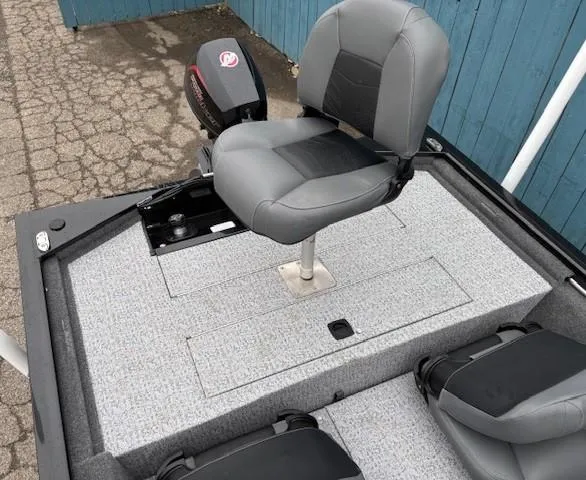 Slide: The Image of 2024 Tracker Pro 170 boat interior with gray seating and motor, parked on a paved surface. - 23