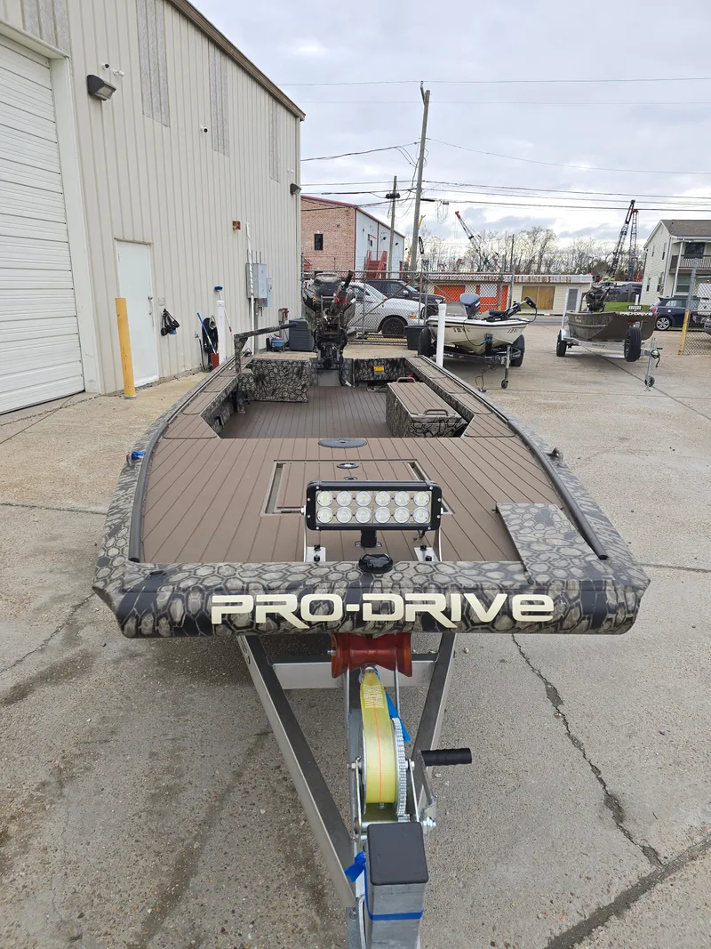 Slide: The Image of 2025 Pro-Drive 1854 boat on trailer, parked outdoors near industrial buildings. - 6