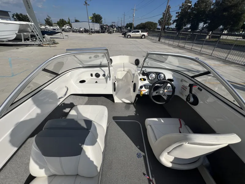 Slide: The Image of 2016 Bayliner 175 boat interior with steering wheel and seating, parked outdoors. - 11