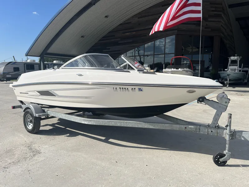 Slide: The Image of 2016 Bayliner 175 boat on trailer, parked outdoors with American flag in background. - 8