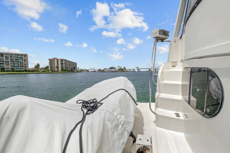Slide: The Image of 2002 Silverton 43 Motor Yacht on water with covered equipment, clear sky, and distant buildings. - 29
