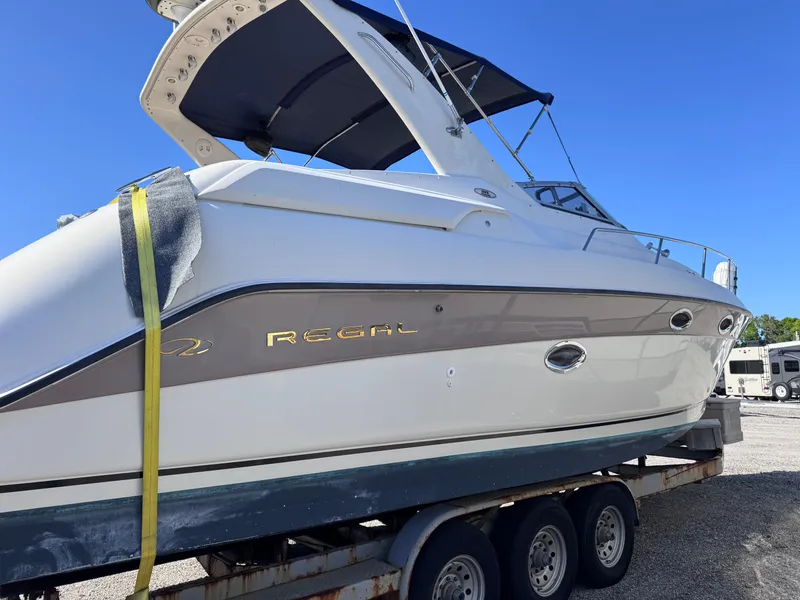 Slide: The Image of 1999 Regal 322 Commodore boat on trailer, white hull, blue canopy, sunny day. - 10