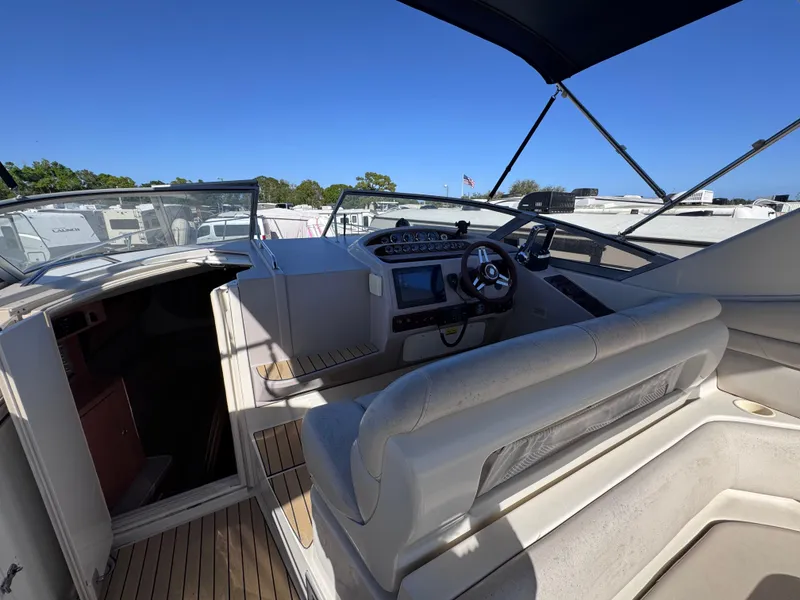 Slide: The Image of 1999 Regal 322 Commodore boat interior with helm and seating area under blue sky. - 32