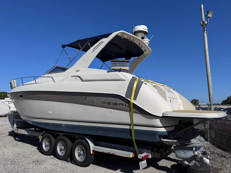 Slide: The Image of 1999 Regal 322 Commodore boat on trailer, parked outdoors under clear blue sky. - 4