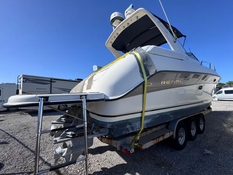 Slide: The Image of 1999 Regal 322 Commodore boat on trailer, parked outdoors under clear blue sky. - 7