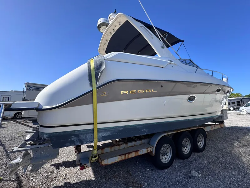 Slide: The Image of 1999 Regal 322 Commodore boat on trailer, parked outdoors under clear blue sky. - 9