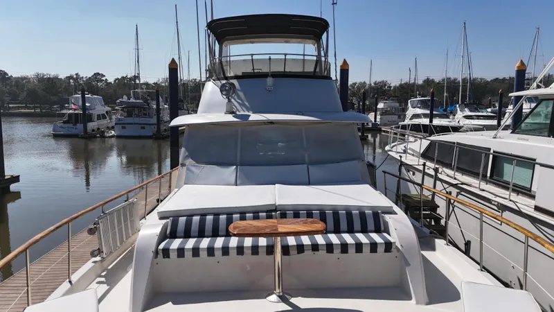 Slide: The Image of 1978 Hatteras 53 Motor Yacht docked, featuring striped seating and a wooden table on deck. - 12