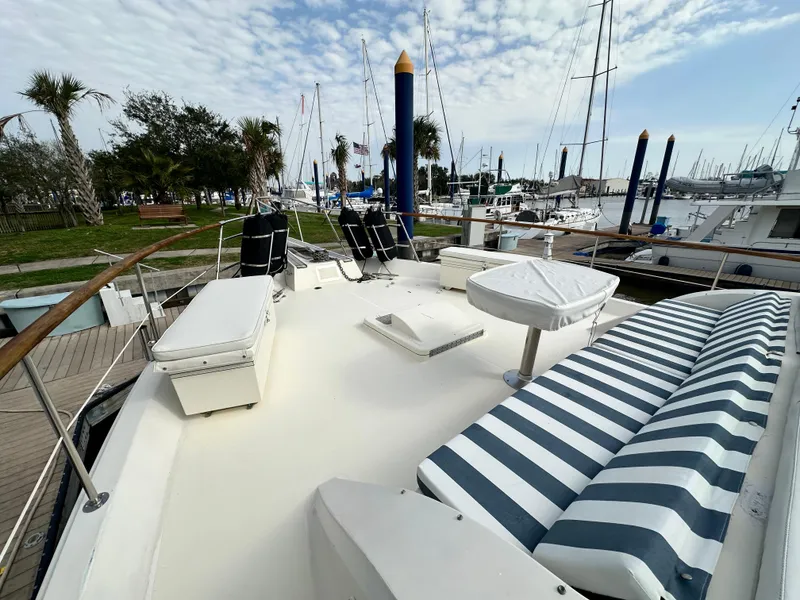 Slide: The Image of 1978 Hatteras 53 Motor Yacht deck with striped seating, docked at marina. - 15