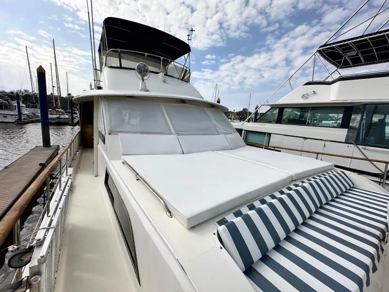 Slide: The Image of 1978 Hatteras 53 Motor Yacht with striped cushions, docked under a partly cloudy sky. - 17