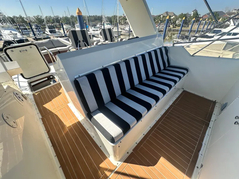 Slide: The Image of 1978 Hatteras 53 Motor Yacht with striped seating on deck, docked at marina. - 30