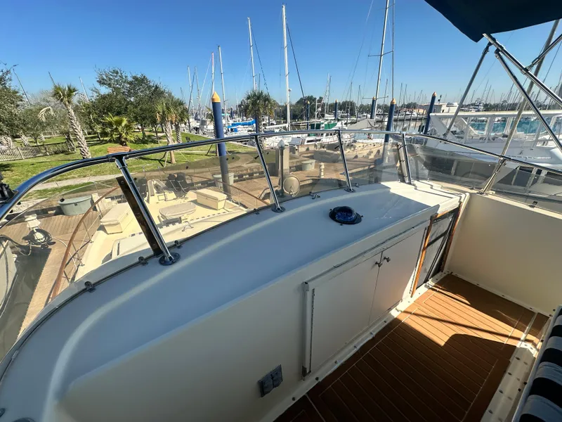 Slide: The Image of 1978 Hatteras 53 Motor Yacht deck with marina view, featuring sleek railing and wooden flooring. - 31