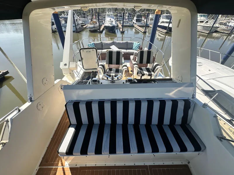Slide: The Image of 1978 Hatteras 53 Motor Yacht with striped seating at a marina. - 32