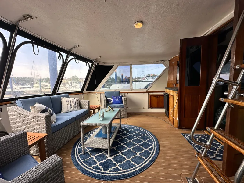 Slide: The Image of 1978 Hatteras 53 Motor Yacht interior with elegant seating, nautical decor, and panoramic windows. - 43
