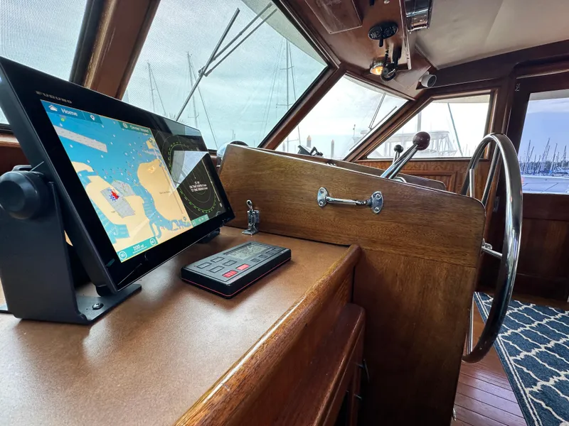 Slide: The Image of 1978 Hatteras 53 Motor Yacht helm with navigation screen and classic wooden steering wheel. - 49