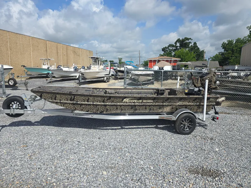 The Image of 2025 Pro-Drive 1848 SBX boat on trailer, parked on gravel lot under cloudy sky. - 0