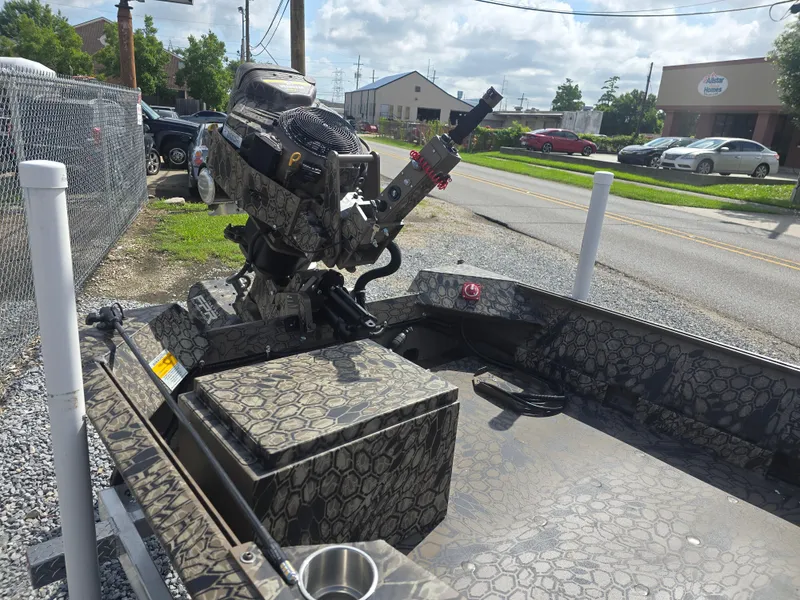 Slide: The Image of 2025 Pro-Drive 1848 SBX boat with camo pattern, parked outdoors on a sunny day. - 11