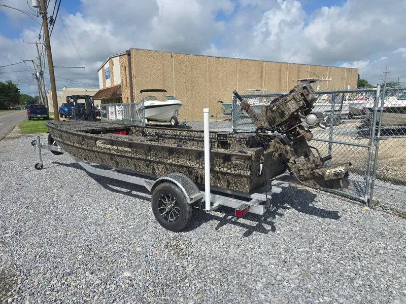 Slide: The Image of 2025 Pro-Drive 1848 SBX boat on trailer, parked on gravel, with industrial background. - 2