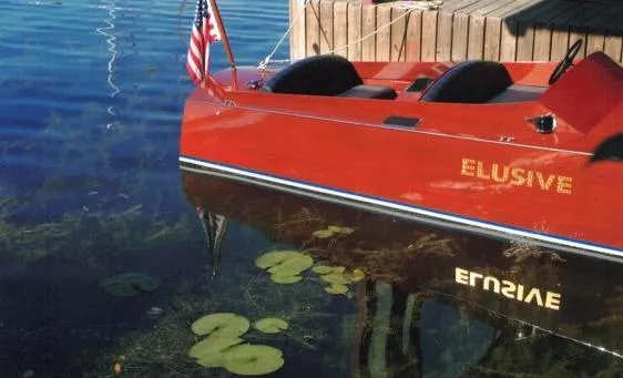 Slide: The Image of Red 2000 Classic Paul Dewhurst Gentleman's Racer boat named "Elusive" docked on clear water. - 3